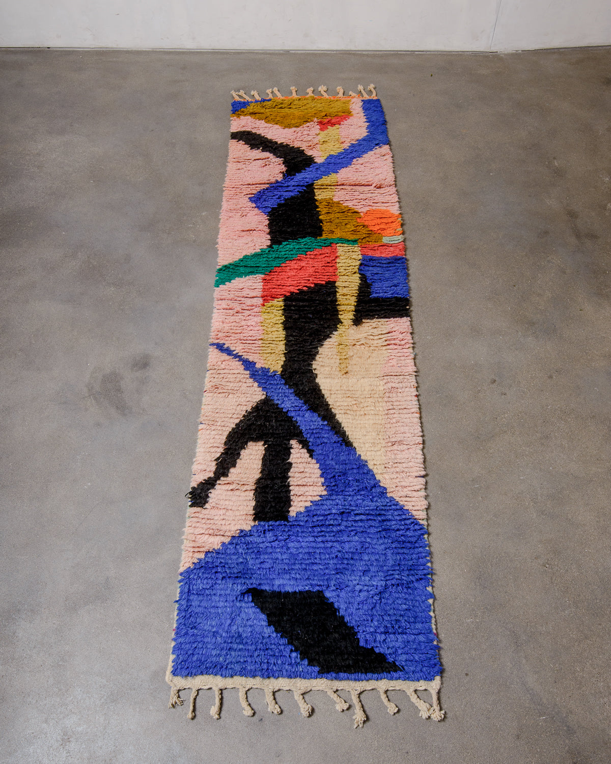 Berberlin vintage runner rug made of brightly coloured wool, laying flat on concrete floor.